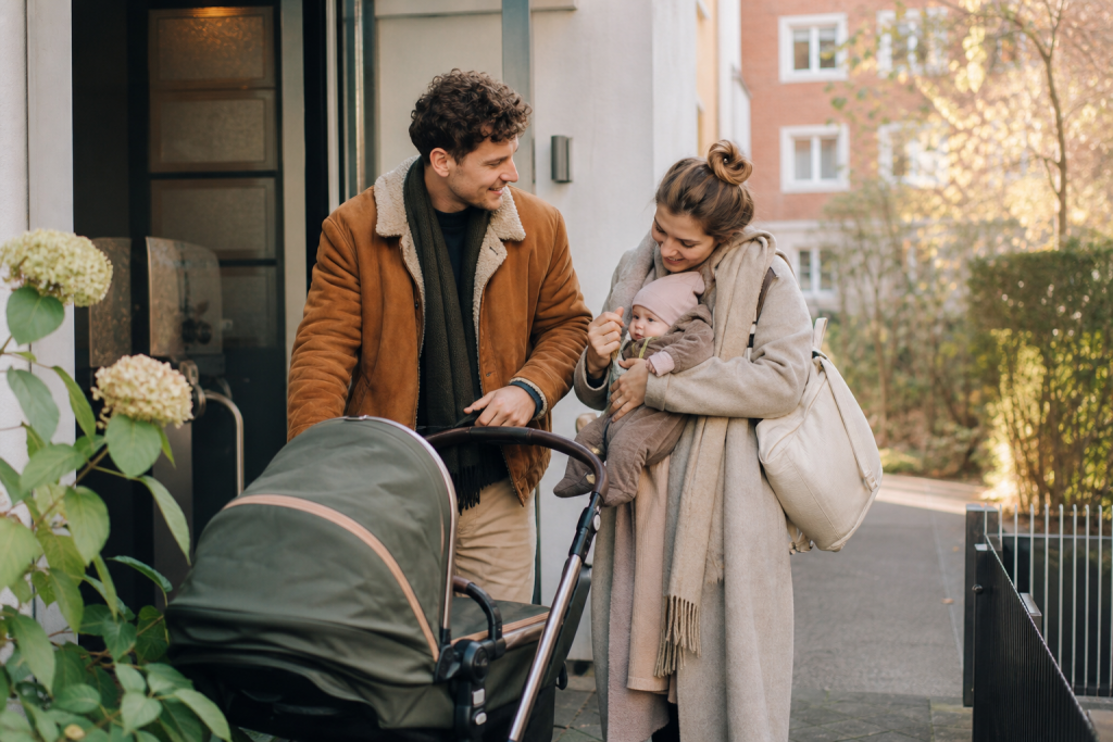 Eltern beim ersten kleinen Ausflug mit Baby und Kinderwagen vor dem Haus